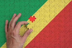 Congo flag  is depicted on a puzzle, which the man's hand completes to fold photo