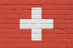 Switzerland flag depicted in paint colors on old brick wall. Textured banner on big brick wall masonry background photo
