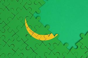 Mauritania flag  is depicted on a completed jigsaw puzzle with free green copy space on the right side photo