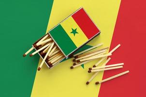 Senegal flag  is shown on an open matchbox, from which several matches fall and lies on a large flag photo
