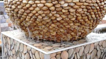 The garden fountain is made out of a jar with several stone beads.Beautiful flowing water on the surface of the rock texture. video