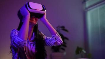 niña que aplica auriculares de realidad virtual durante el trabajo en casa por la noche, concepto de tecnología moderna video