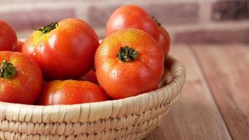 Large tomato lifted from a natural wicker bowl with other tomatoes video