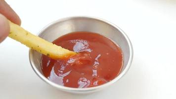 Fry dipping into ketchup container close up video