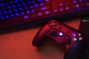 Modern gamepad lies with pc keyboard on table in dark playroom scene. Gameplay streaming and video game walkthroughts concept photo