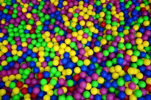 Many colorful plastic balls in a kids' ballpit at a playground. Close up pattern photo