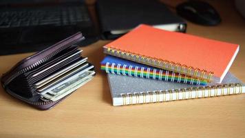 pilha de notebooks e uma carteira aberta na mesa de casa video