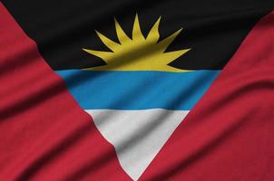 Antigua and Barbuda flag  is depicted on a sports cloth fabric with many folds. Sport team banner photo