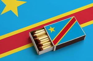Democratic Republic of the Congo flag  is shown in an open matchbox, which is filled with matches and lies on a large flag photo