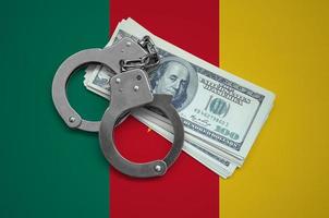 Cameroon flag  with handcuffs and a bundle of dollars. Currency corruption in the country. Financial crimes photo