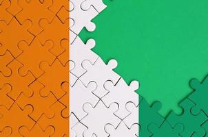 Ivory Coast flag  is depicted on a completed jigsaw puzzle with free green copy space on the right side photo