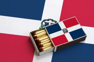 Dominican Republic flag  is shown in an open matchbox, which is filled with matches and lies on a large flag photo