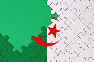 Algeria flag  is depicted on a completed jigsaw puzzle with free green copy space on the left side photo