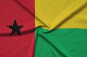 Guinea Bissau flag  is depicted on a sports cloth fabric with many folds. Sport team banner photo