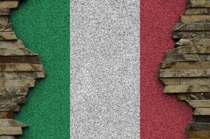 Italy flag depicted in paint colors on old stone wall closeup. Textured banner on rock wall background photo