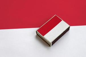 Monaco flag  is pictured on a matchbox that lies on a large flag photo