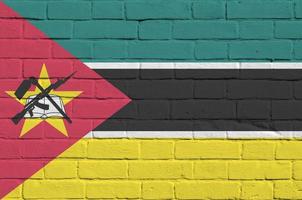 Mozambique flag depicted in paint colors on old brick wall. Textured banner on big brick wall masonry background photo