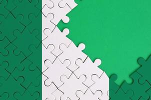 Nigeria flag  is depicted on a completed jigsaw puzzle with free green copy space on the right side photo