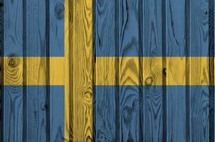 Sweden flag depicted in bright paint colors on old wooden wall. Textured banner on rough background photo