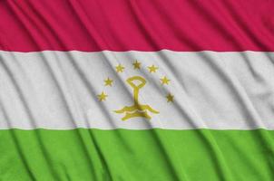 Tajikistan flag  is depicted on a sports cloth fabric with many folds. Sport team banner photo