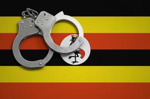 Uganda flag  and police handcuffs. The concept of crime and offenses in the country photo