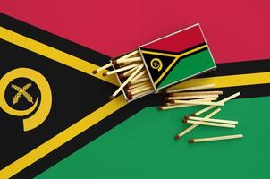 Vanuatu flag  is shown on an open matchbox, from which several matches fall and lies on a large flag photo