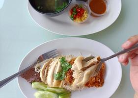 Boiled chicken rice on a spoon served with soup and dipping sauce, top view. The most popular street food in Thailand is called Khao Mun Gai. photo