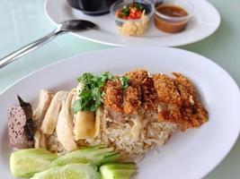 steamed rice topped with boiled chicken Mixed with Fried Chicken Served with broth and dipping sauce, side view. The most popular street food in Thailand is called Khao Mun Gai. photo