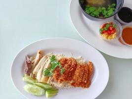 arroz al vapor cubierto con pollo hervido mezclado con pollo frito servido con caldo y salsa, vista superior. la comida callejera más popular en tailandia se llama khao mun gai. foto