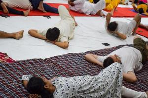 New Delhi, India, June 19 2022 -Group Yoga exercise session for people of different age groups in Balaji Temple, Vivek Vihar, International Yoga Day, Big group of adults attending yoga class in temple photo