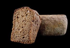 Whole and half loaf of rye bread isolated on black background. photo