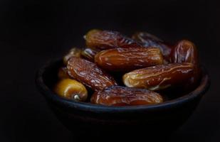 Clay bowl of ripe beautiful dates. Dried dates on a brown background. photo