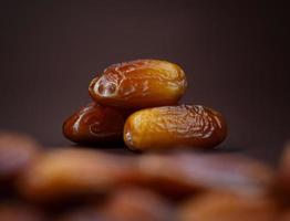 Dates lie on the background of other dates. Ripe dried dates. photo