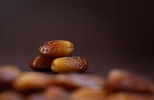 Dates lie on the background of other dates. Ripe dried dates. photo