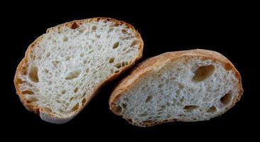 Ciabatta, a loaf of bread cut in half isolated on a black background. photo