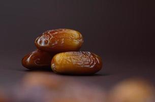 Three ripe delicious dates lie on a brown background. photo