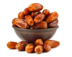 A clay bowl full of dried dates is isolated on a white background. Full clipping path. photo