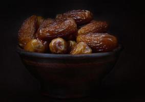 Clay bowl of ripe beautiful dates. Dried dates on a brown background. photo