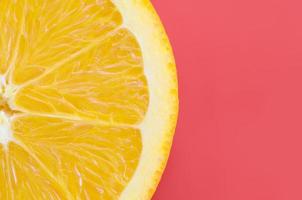 Top view of a one orange fruit slice on bright background in red color. A saturated citrus texture image photo