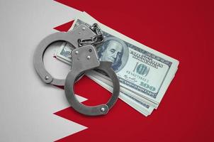Bahrain flag  with handcuffs and a bundle of dollars. Currency corruption in the country. Financial crimes photo