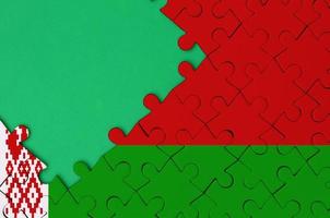 Belarus flag  is depicted on a completed jigsaw puzzle with free green copy space on the left side photo