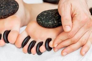 Hot little black stones between female toes photo