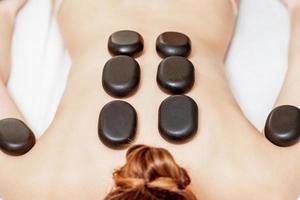 Black hot stones lying on female back photo