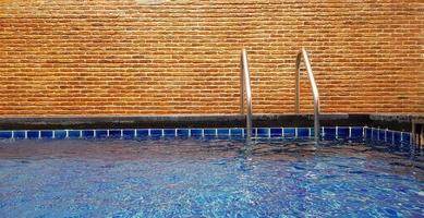 Swimming pool with stair and brick wall background with copy space. Interior design and Structure. photo