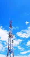 Red and white telecommunication, broadcast TV, digital television, radio, Transmission, microwave or mobile tower with blue sky and cloud background and copy space. Technology and telecom equipment photo