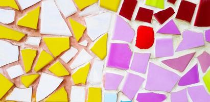 colorido del suelo de baldosas de mosaico para el fondo. papel pintado de diseño de arte, agrietado, forma y abstracto. fragmentos de baldosas blancas, rojas, amarillas, moradas o violetas en la pared. foto