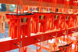 kyoto, japón - 25 de febrero de 2020 muchas pequeñas puertas torii colgando de una percha de madera roja en el santuario fushimi inanari. la gente escribe bendiciones en amuletos y reza para que sea verdad. foto