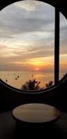 silueta de mesa y ventana con mar, cielo, cocotero y fondo de puesta de sol o amanecer en la playa de bangsaen chonburi, tailandia. paisaje marino con luz solar y vistas al paisaje foto