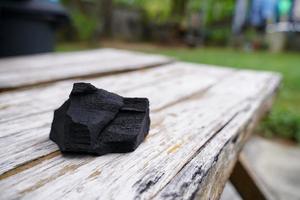 carbón negro sobre fondo de madera vieja, el carbón es esencial para asar a la parrilla. foto