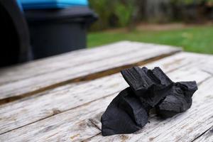 Black charcoal on old wood background, Charcoal is essential in grilling. photo